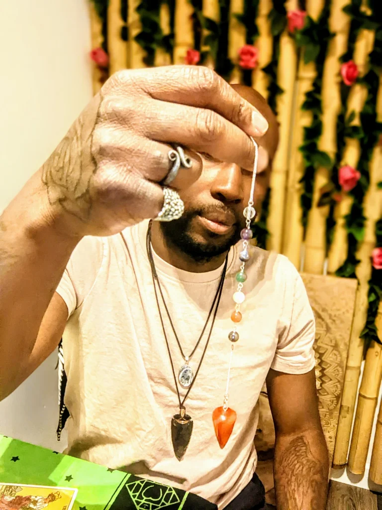 Image of Dru holding a crystal pendulum. Reiki East London at The Holding Space